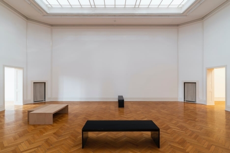 Park McArthur, <em>A view of Kunsthalle Bern’s main gallery space: light blue ceiling tiles vented upwards, white walls and crown molding, parquet wooden flooring the color of honey. The ceiling’s large circle, star, and grid design elements fill the image’s upper half. A small, two page artwork titled Form found figuring it out, show, 2020 is barely visible from across the large room and two black museum benches sit perpendicular to one another on the floor</em>